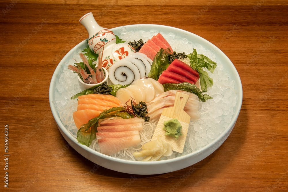 Great tray of sea bass sashimi sushi, squid with seaweed, Norwegian salmon, butterfish and yellowfin bluefin tuna on a lot of crushed ice