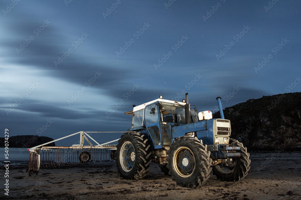 Seaweed collector tractor resting on the Asturias beach in the middle of the night