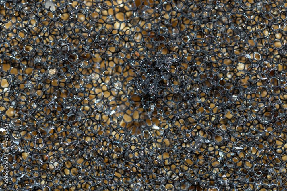 Household dishwashing sponge from reticulated foam, texture, background. Surface of black sponge for washing dishes, pattern closeup