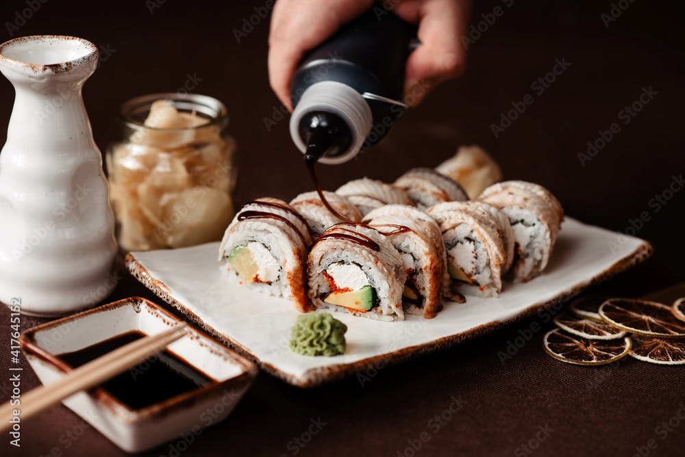 Chef pours white eel sushi with sauce