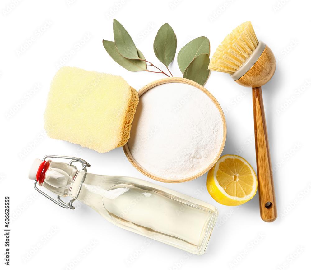 Bowl of baking soda, vinegar, cleaning brush, sponge and lemon on white background