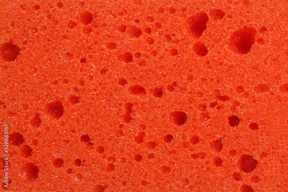 Texture, background of a red sponge for washing dishes or showering close up, macro