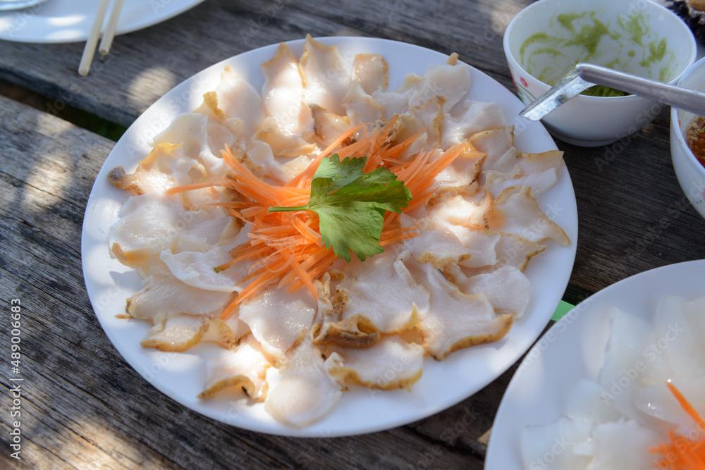 Selective focus on the meat of the Murex shell, Ramose Murex, Shellfish is slice into thin pieces serves on white dish.