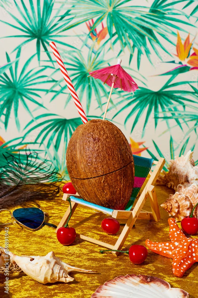 coconut ornamented with a paper umbrella on a small deck chair