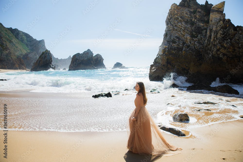 Young beautiful caucasian woman in long tull dress on coast of sea.
