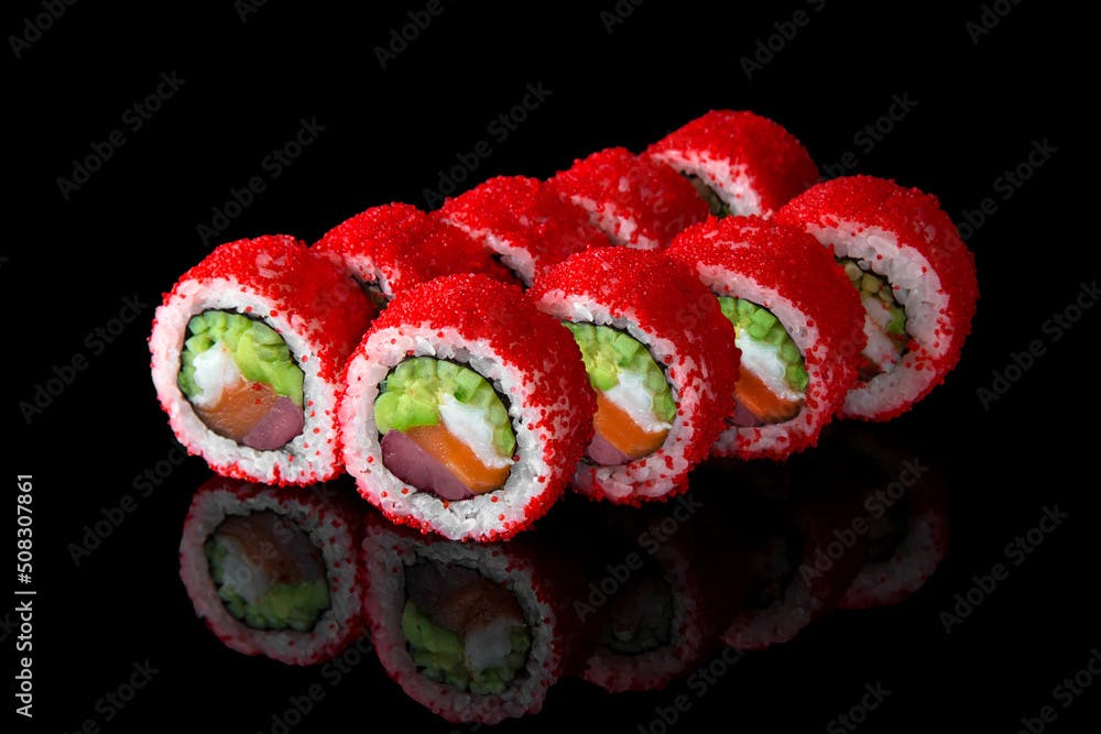 Sushi roll royal california with tuna, salmon, perch, avocado and tobiko caviar on black background. Sushi menu. Japanese food.