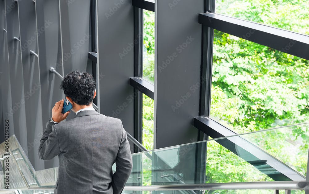 階段でスマホを使って通話する男性