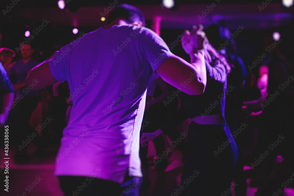 Couples dancing traditional latin argentinian dance milonga in the ballroom, tango salsa bachata kizomba lesson in the red, purple and violet lights, dance festival