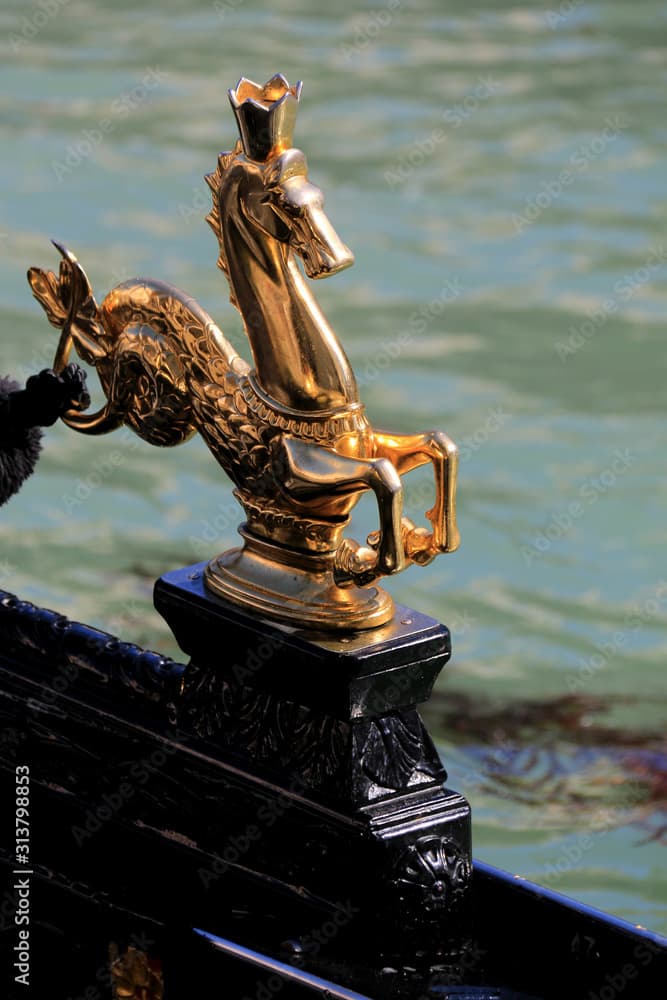 Golden sea horse statue with crown decorating a gondola on the Canal Grande in Venice, Italy