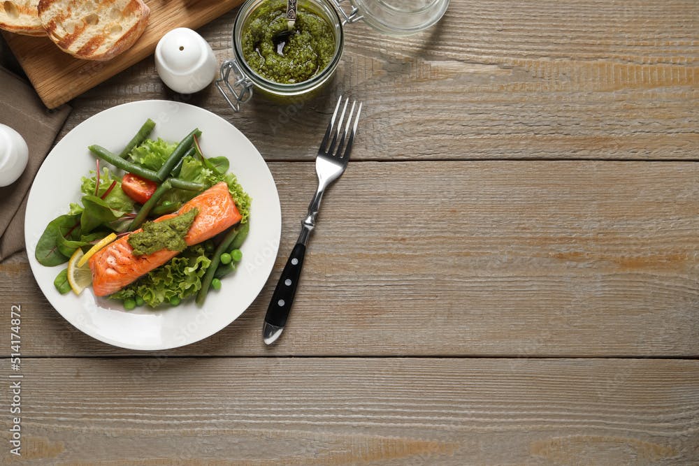 Tasty cooked salmon with pesto sauce served on wooden table, flat lay. Space for text