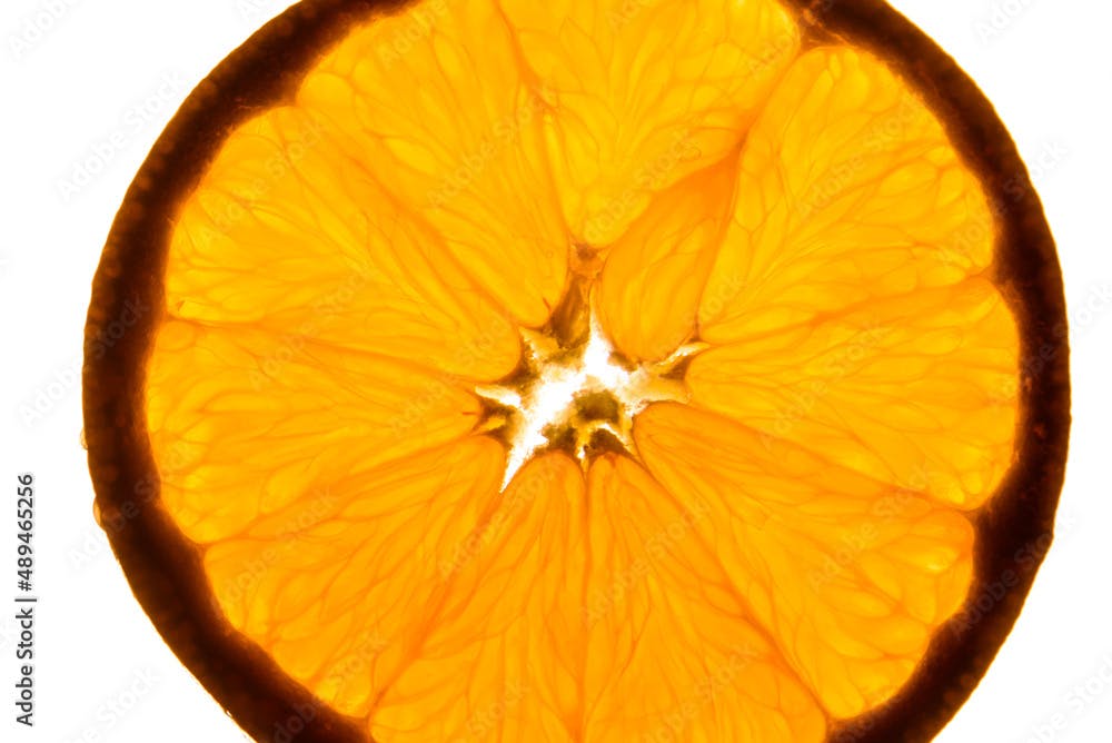 Slice of orange back lit, macro view from above of glowing detail

