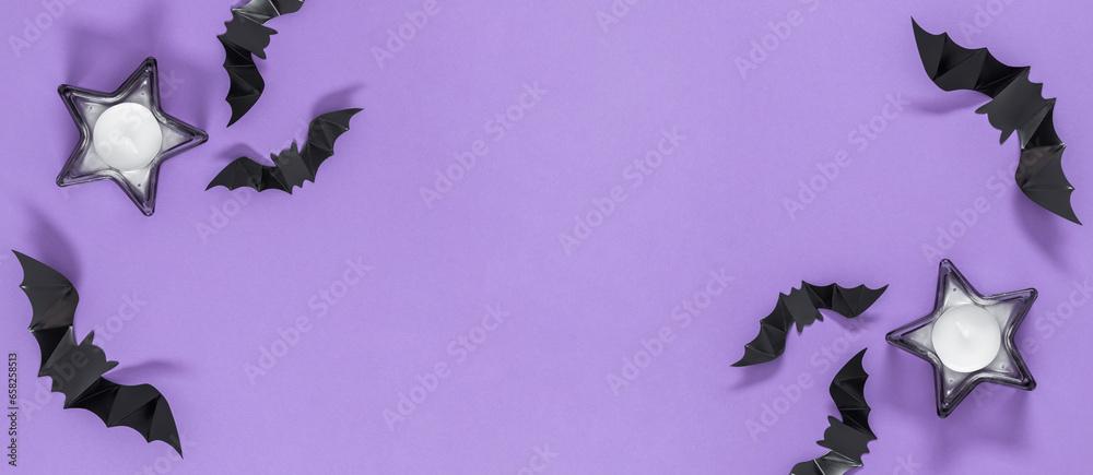 Halloween sale concept. Holiday decorations for Halloween with paper bats star shaped candles on purple background. Flat lay, top view, copy space